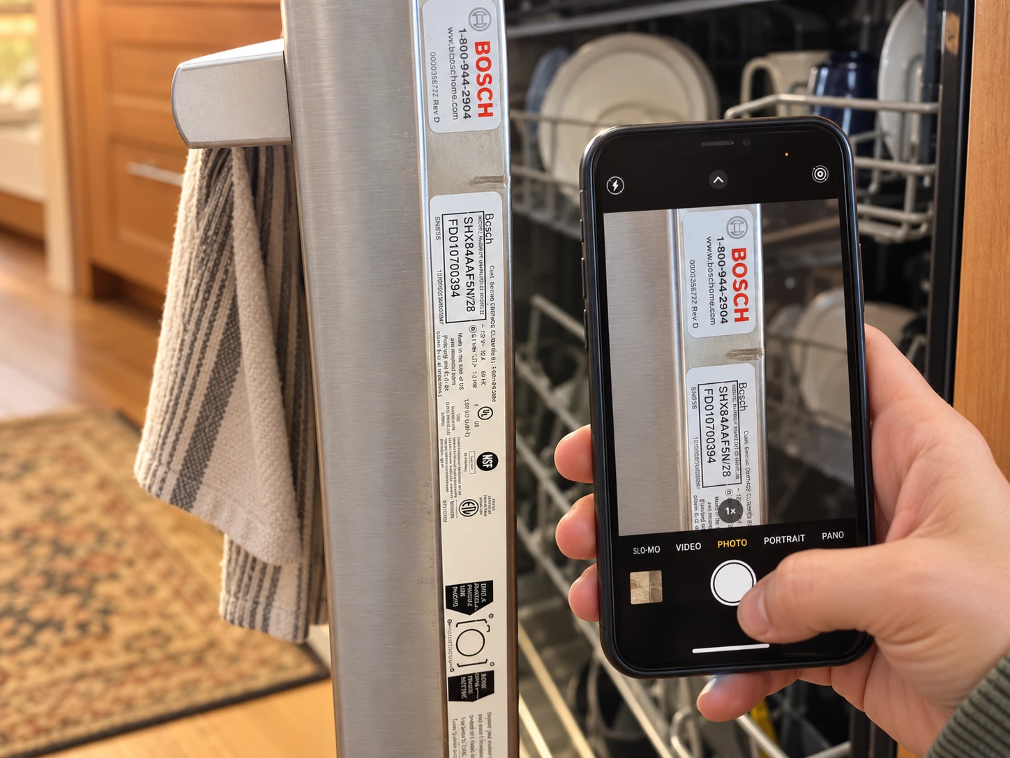 A phone photographing the Bosch model label on an open dishwasher door edge